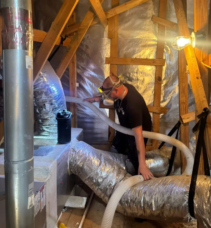 Technician adding insulation around HVAC ductwork in a residential attic