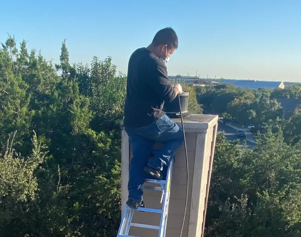 Technician cleaning the chimney on the roof