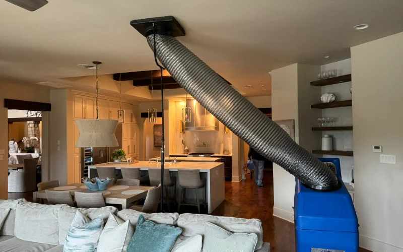 Air duct cleaning equipment connected to a ceiling vent in a residential home.