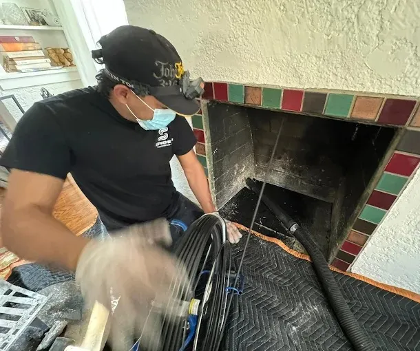 Technician performing fireplace and chimney cleaning in a residential home.